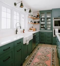 a kitchen with green cabinets and white counter tops, an area rug on the floor