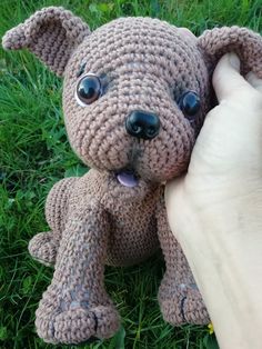 a crocheted dog is being held by someone's hand in the grass