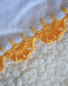 an orange piece of fabric is laying on top of some white material and it looks to be crocheted