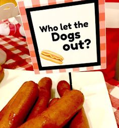 two hot dogs on a plate with a sign that says who let the dogs out?