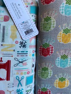 the fabric is colorful and has scissors, apples, and sewing needles on it with a price tag