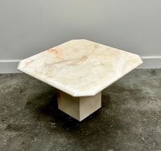 a square marble table sitting on top of a cement floor