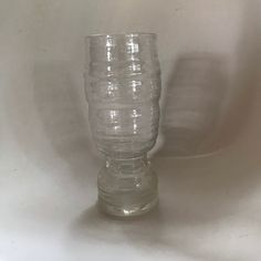 a clear glass vase sitting on top of a white tableclothed surface with no one around it