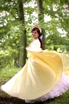 a woman in a yellow dress is walking through the woods wearing a hat and gown