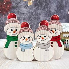 three wooden snowmen with hats and scarves