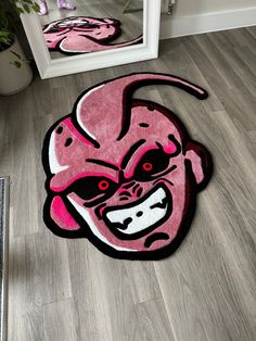 a pink rug with an angry face on the floor next to a mirror and door