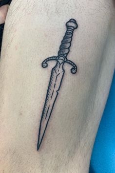 a knife tattoo on the side of a mans leg, with a rope wrapped around it