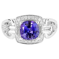 a purple and white diamond ring with two baguets on the sides, set in 18k white gold