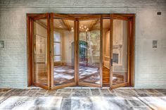 an open glass door in front of a white brick wall with wood trimmings