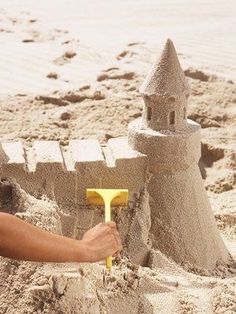 a sand castle made to look like it has a shovel in it and is being held by someone's hand