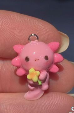 a small pink toy with a flower in it's mouth on someones finger