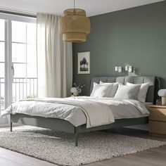 a bedroom with green walls and white linens on the bed, along with an area rug