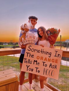 a man and woman standing on a wooden deck holding signs that say something in the orange tells me to ask you to go