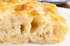 a close up of a piece of bread on a white plate with a blue and white bowl in the background