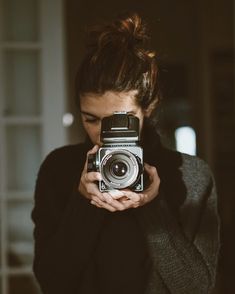 black and white photograph of a woman taking a photo with an old camera in front of her