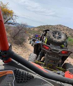 four people riding atvs down a dirt road