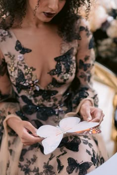 a woman in a dress holding a butterfly shaped paper plate and looking down at it