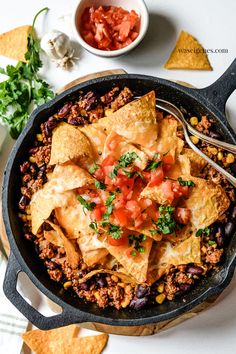 a skillet filled with mexican food and tortilla chips on top of a table