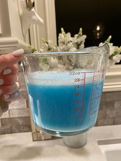 a person holding a measuring cup filled with blue liquid