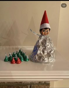 an elf doll sitting on top of a table next to candy bars and wrapped in tin foil