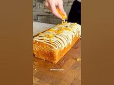 a person is decorating a loaf of bread with icing and orange zest