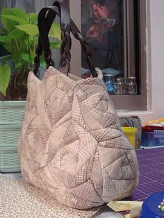 a purse sitting on top of a table next to a blue bowl and planter