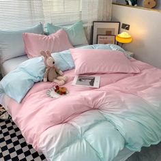 a bed with pink and blue sheets, pillows and a stuffed animal sitting on it