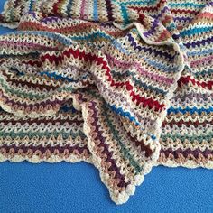 a crocheted blanket laying on top of a blue surface