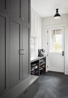 an empty entryway with gray cabinets and shoes on the shelf next to the door