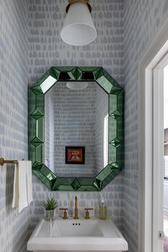 a bathroom sink under a mirror next to a wall mounted faucet and light fixture