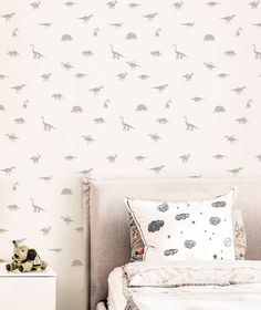 a child's bedroom with dinosaur wallpaper and a bed in the foreground