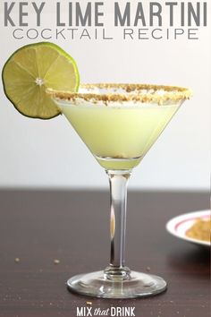 a green drink with a slice of lime on the rim next to a small plate