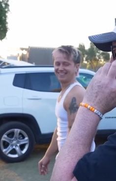 a man talking on a cell phone while standing next to another man in a parking lot