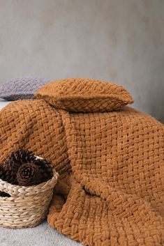 a basket filled with pine cones sitting on top of a bed next to two blankets