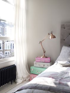 three suitcases stacked on top of each other in front of a bed with a lamp