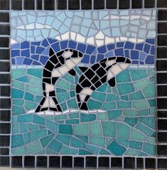 two dolphins swimming in the ocean on a mosaic tile wall