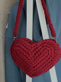 a crocheted heart shaped purse hanging from a hook on the back of a chair