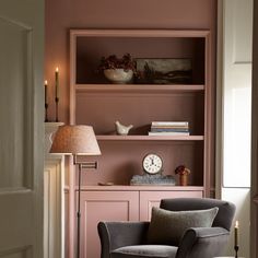 a living room filled with furniture and a clock on top of a book shelf next to a lamp