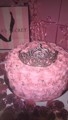 a pink cake with a tiara on top surrounded by pennets and other decorations