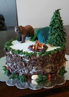 there is a cake that looks like a forest scene with a bear and tent on top