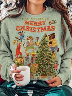 a woman is holding a coffee cup and wearing a sweatshirt with the words merry christmas on it