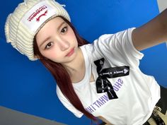 a girl with red hair wearing a white t - shirt and a knitted hat