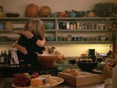 two people hugging in the kitchen with food on the counter