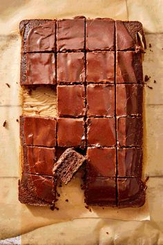 a piece of chocolate cake is cut into squares and sits on a piece of parchment paper