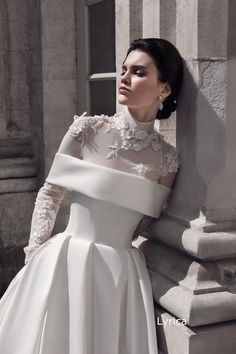 a woman in a white dress leaning against a wall