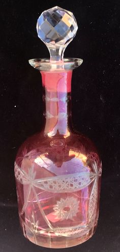 This beautiful, vintage etched glass liquor decanter has a light ruby tint which, together with the clear glass incisions in the bottom half of the bottle's surface , allow the color of whatever liquor you put it in to be seen and appreciated. The decanter has a weighted, faceted crystal stopper and stands 10 1/2" tall with a bottom diameter of 3 1/2." Not sure of the capacity in ml but it will accommodate the contents of a fifth of bourbon, scotch, or vodka easily enough. Whisky Decanter, Liquor Decanter, Etched Glass, Decanters, Glass Etching, Faceted Crystal, Liqueur, Clear Crystal, Scotch