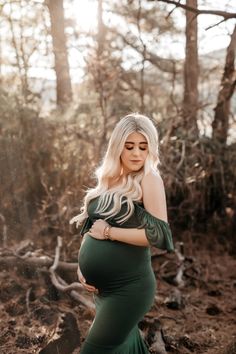 a pregnant woman wearing a green dress in the woods