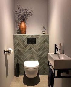 a white toilet sitting next to a bathroom sink under a brown vase on top of a shelf