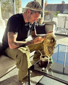 a man sitting on top of a couch next to a glass table filled with plants