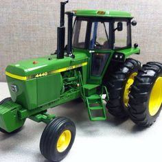 a green tractor with yellow wheels on a white surface